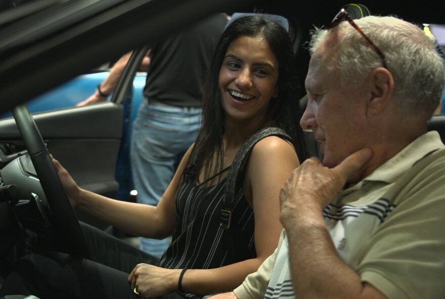 People seated in a stationary car with the door open.