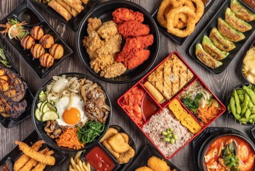 Looking down on a table full of an assortment of Korean dishes. 