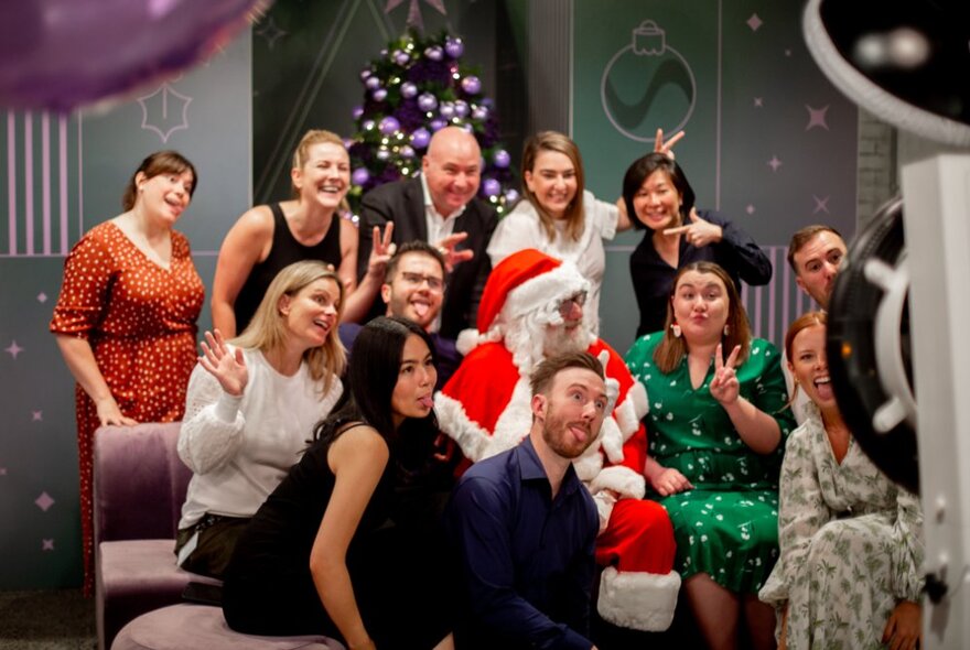 A group of adults posing for a photo with Santa. 