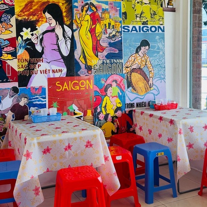 Plastic stools and tables in a small cafe with poster-lined wall.