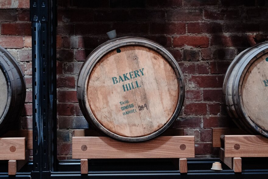 A whisky barrel with the words Baker Hill stamped on it, in an underground cellar lined with brick.