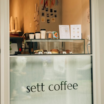 The coffee serving window at Sett Coffee with cakes of display and samples of cup sizes. 