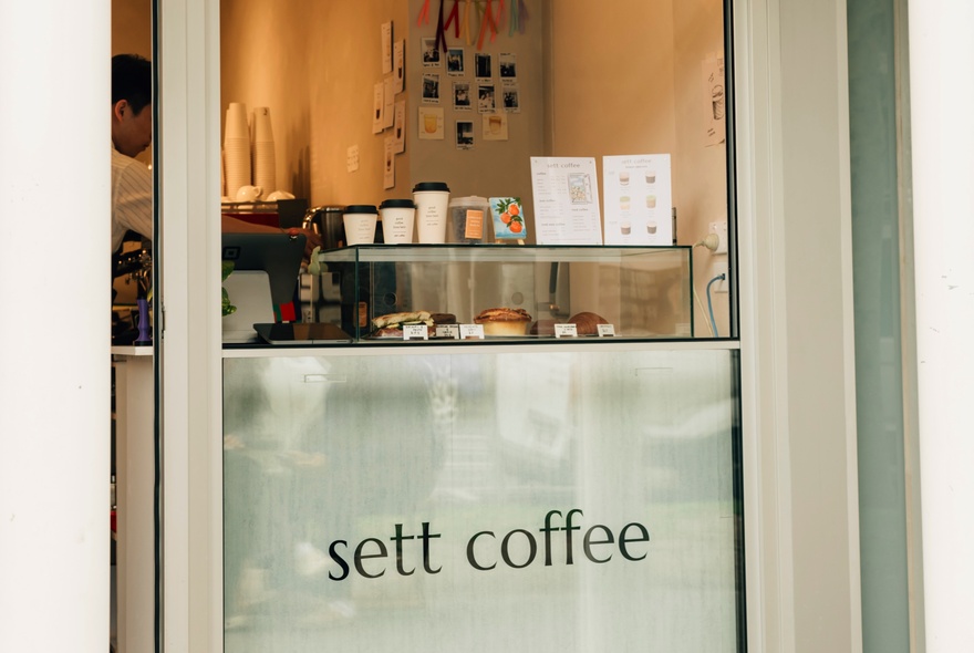 The coffee serving window at Sett Coffee with cakes of display and samples of cup sizes. 
