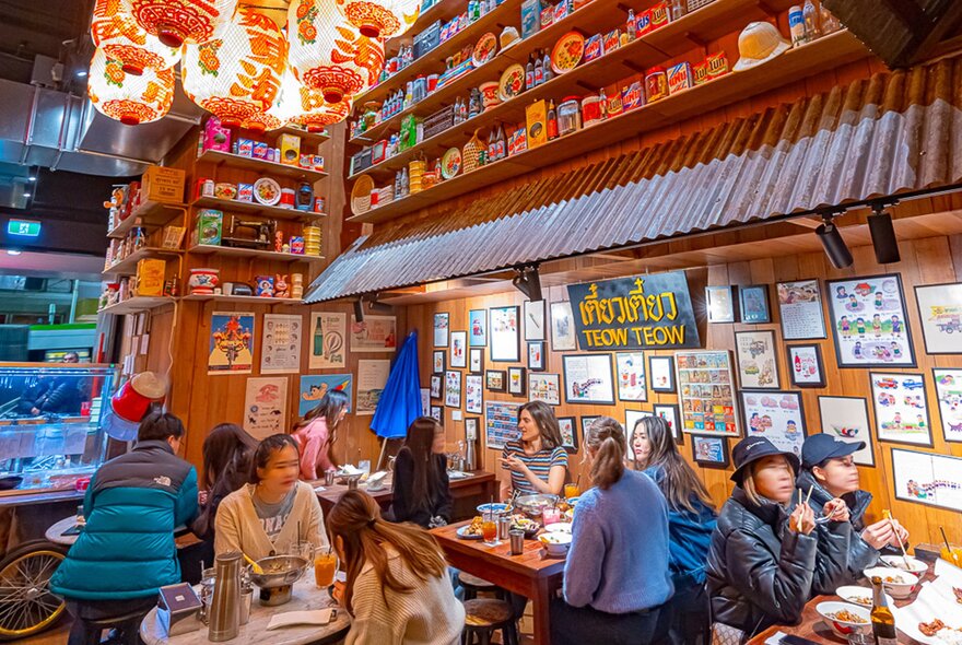 Inside a busy Thai restaurant with vintage decor and lanterns hanging from the ceiling