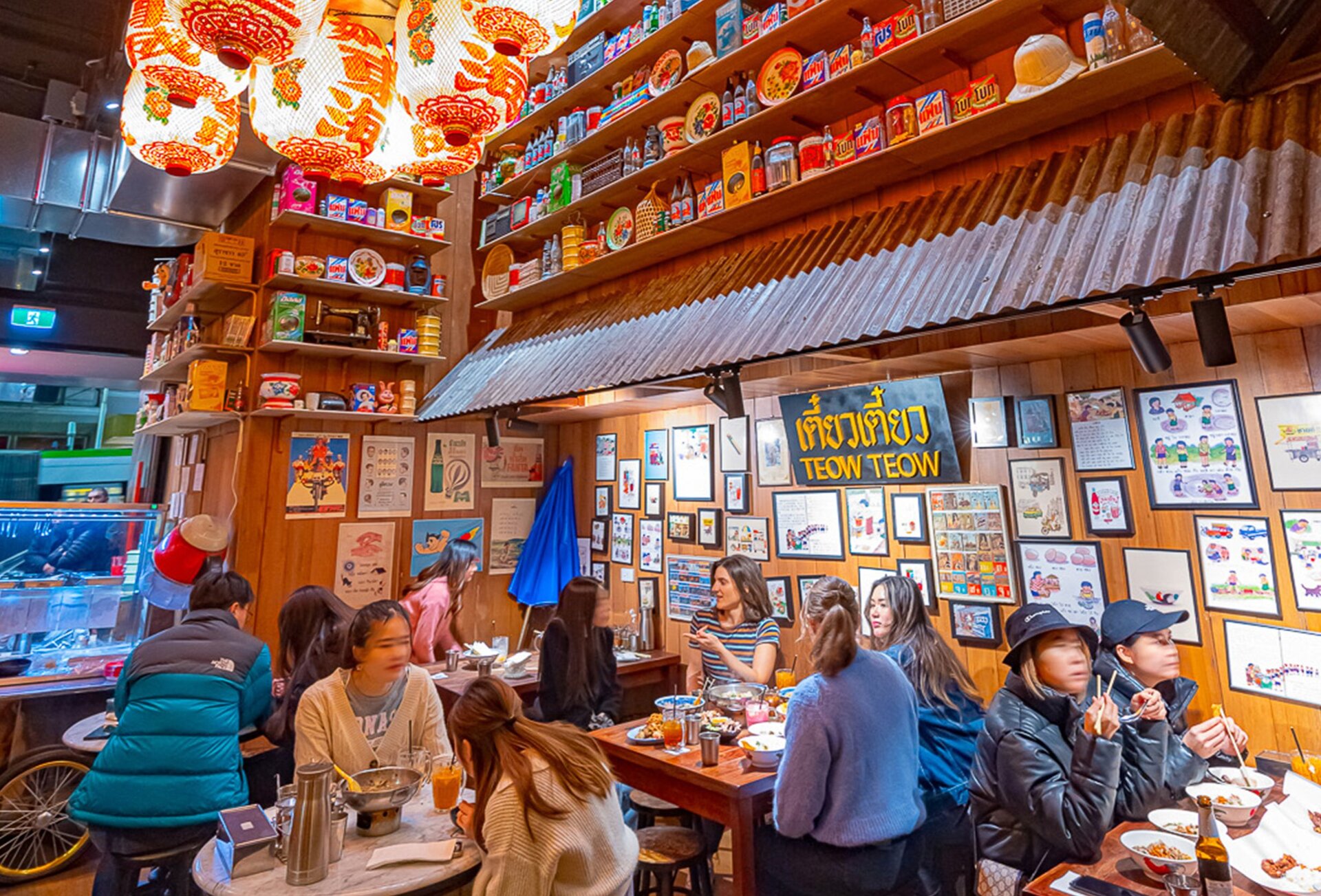 Inside a busy Thai restaurant with vintage decor and lanterns hanging from the ceiling