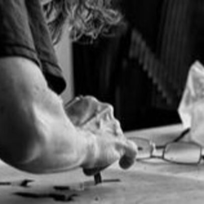 Black and white photograph of an artist using oil crayons to create an artwork.