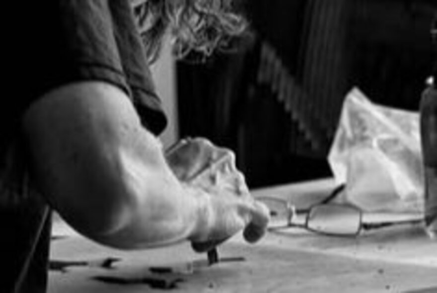 Black and white photograph of an artist using oil crayons to create an artwork.