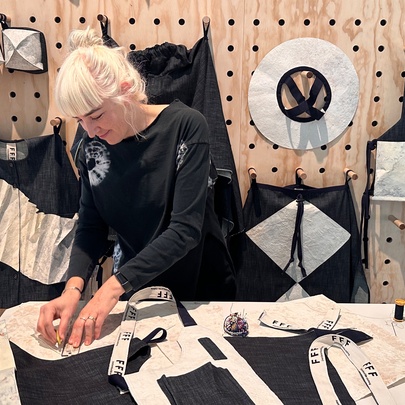 A person with platinum blonde hair working on a project using fabric in a workshop environment. 