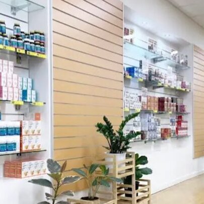 Interior of a retail space, with products displayed on shelves on a wall, green plants in pots and a shiny timber floor.