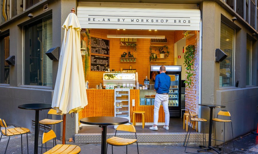 A man ordering at the counter of an orange tiled hole in the wall cafe. 