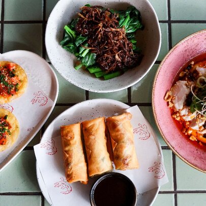 Four share plates of Asian food.