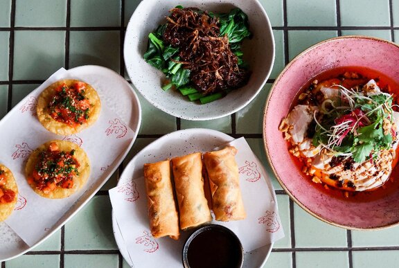 Four share plates of Asian food.