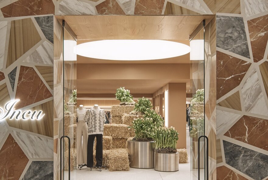 View through the open glass doors of the shop Incu with two clothed mannequins on display inside the space.