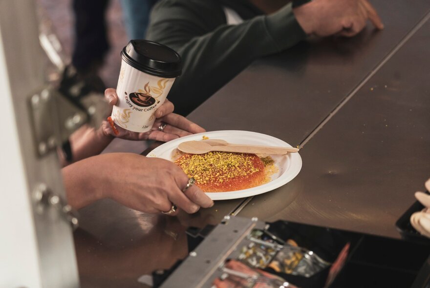 Hands holding a dish of Middle Eastern food and keep cup.