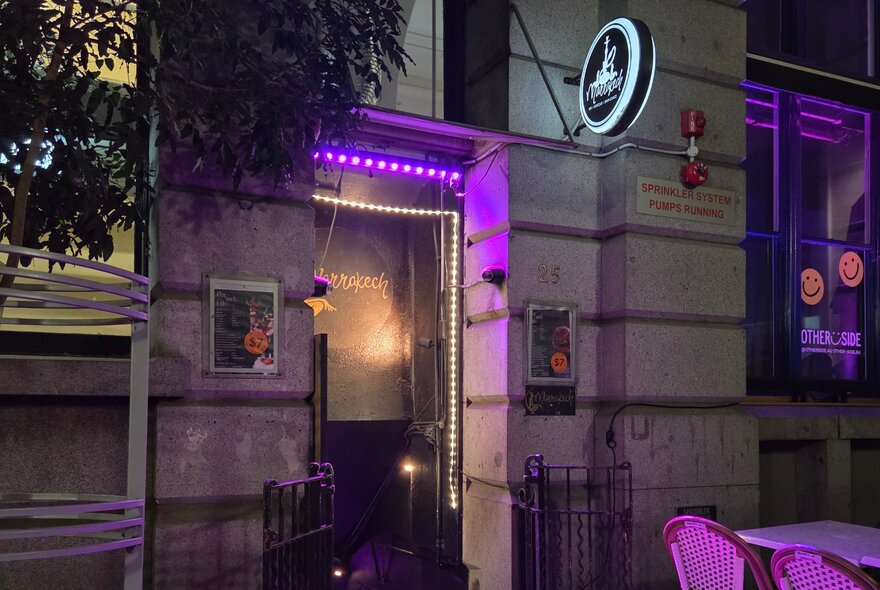 Venue doorway lit by purple and white lights at night, with signage.