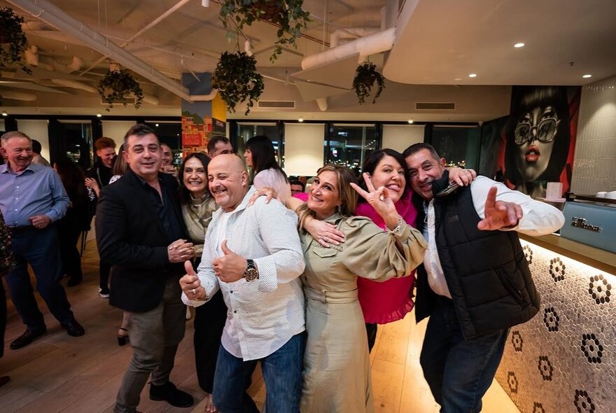 People mugging for the camera in a restaurant setting on a small dance floor next to a bar.