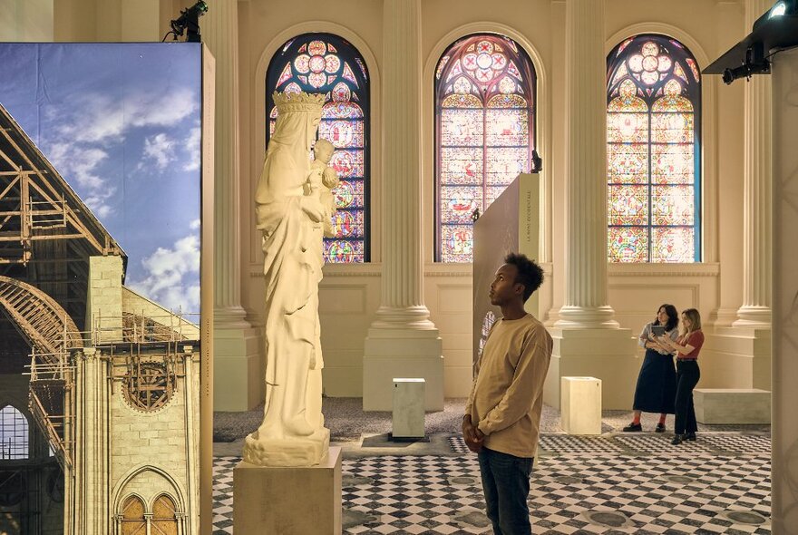 A museum patron looking at a statue at the Notre Dame exhibition. 