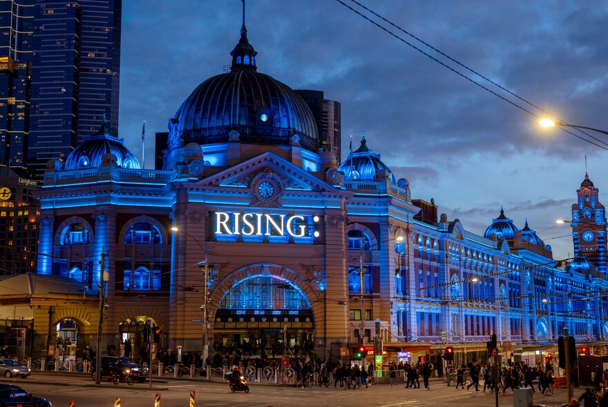 Flinders Street Station lit up in blue lights at night for Rising festival.