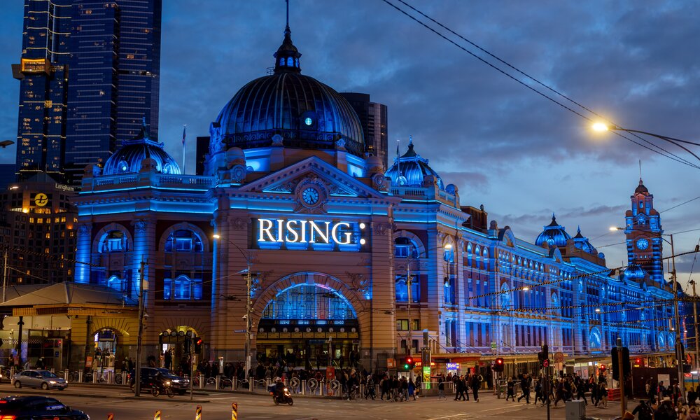 Flinders Street Station lit up in blue lights at night for Rising festival.