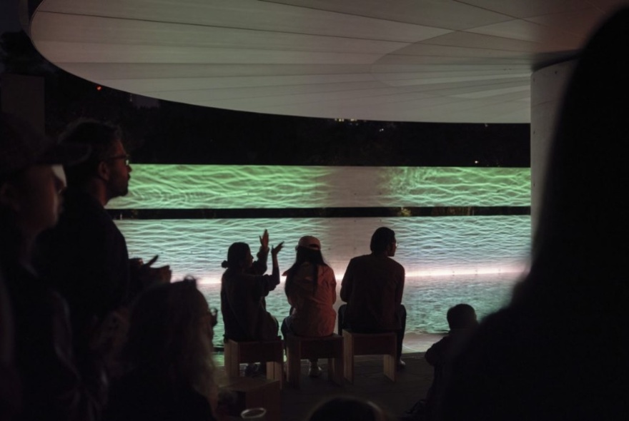 Silhouettes of people in an underground area with ripples of water on the walls. 