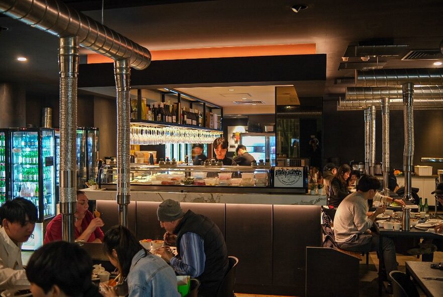 Interior with patrons tucking into food, and bar/kitchen at rear.