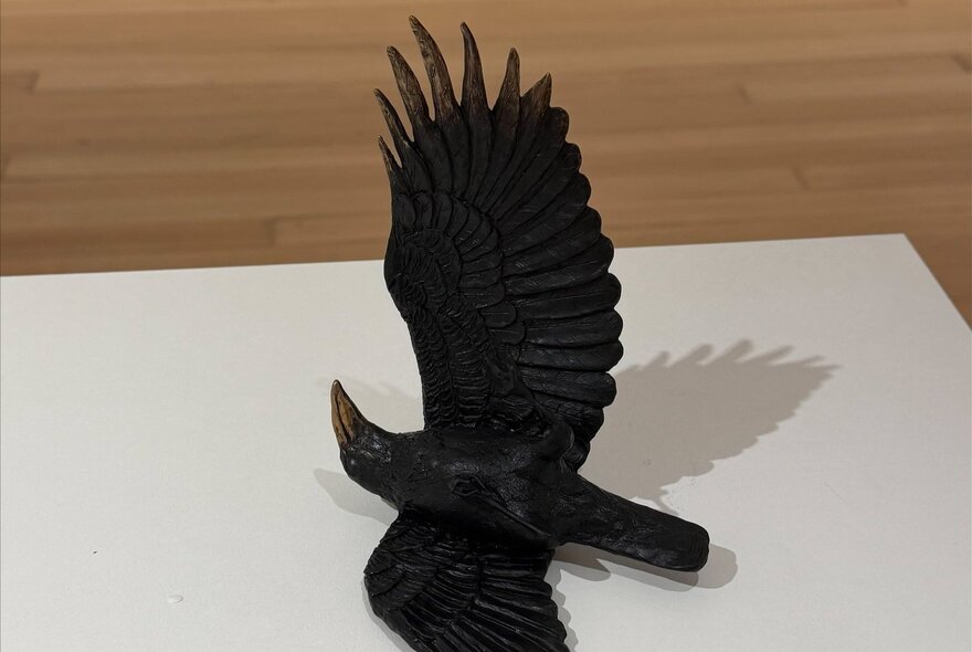 Sculpture of a black bird with wings open.