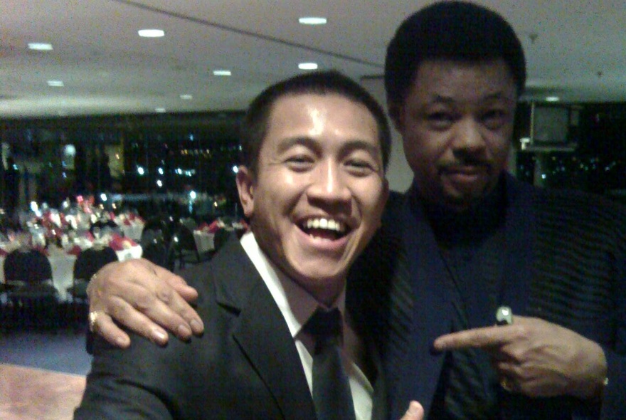 Comedian Anh Do and another person posing for a selfie in a ballroom.