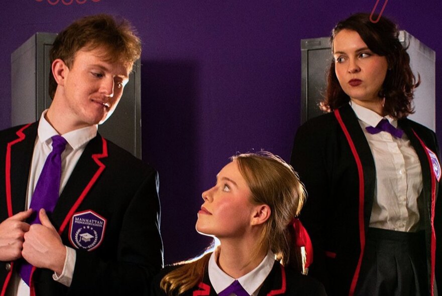 Three young people exchanging looks in school blazers in a purple room. 