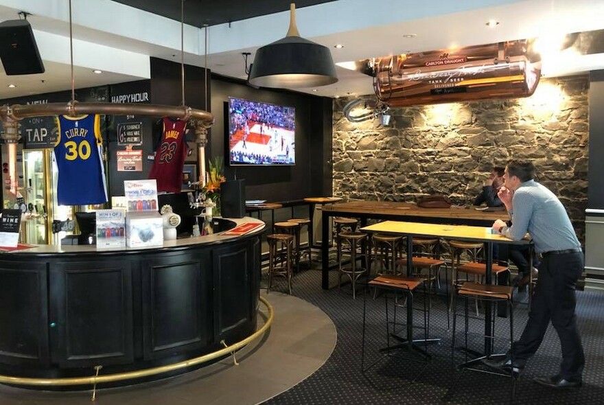 Interior of the Copper Inn showing rounded bar area, and a patron watching sport on a TV screen.