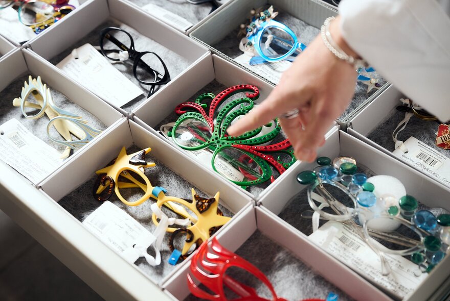 A drawer with compartments containing novelty glasses.
