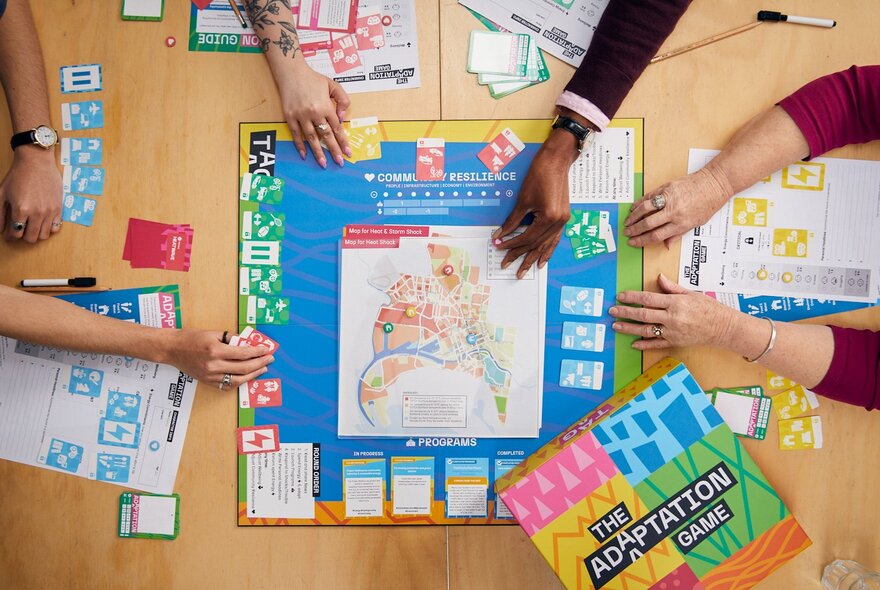 A tabletop board game seen from above, with people hands moving pieces on the board.