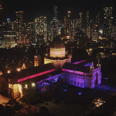 A large building lit up purple in the city at night.