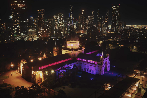 A large building lit up purple in the city at night.