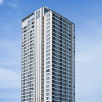 A lone skyscraper against a blue sky with wispy clouds.