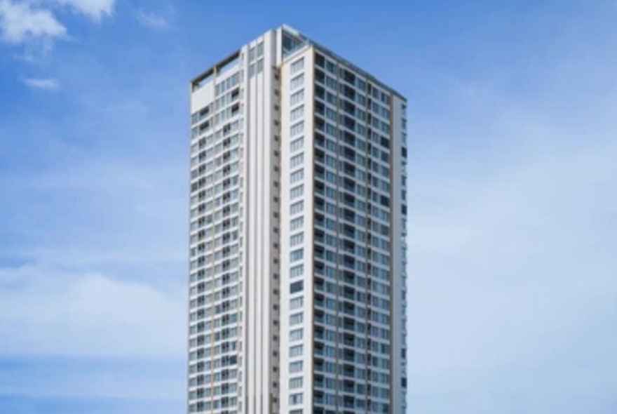 A lone skyscraper against a blue sky with wispy clouds.