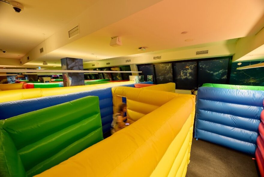 Padded room dividers creating a maze with different coloured sections in a large venue.