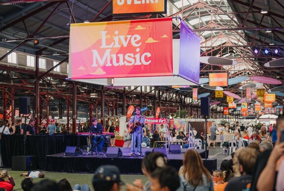 Crowds watching live music on stage in a shed.
