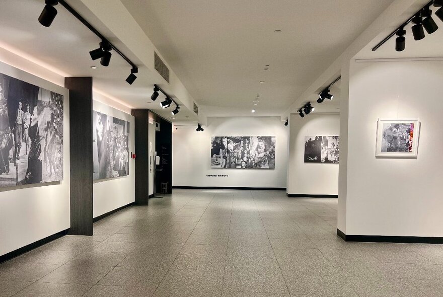 A gallery space with black and white collage prints displayed on the wall.