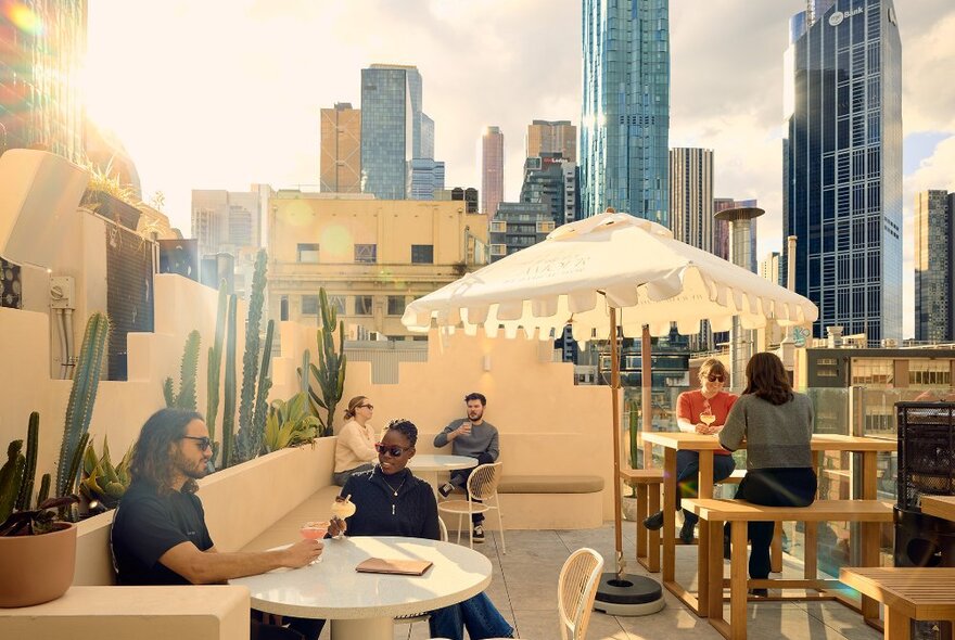 People drinking margaritas on a Mexican inspired rooftop bar with cacti.