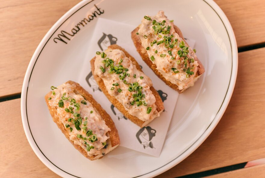 Three lobster rolls on an oval platter.