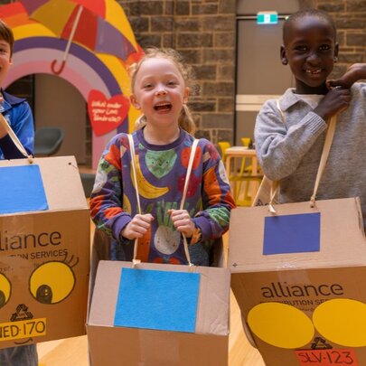 Three young children wearing cardboard box car creations.