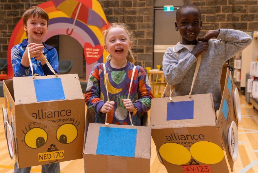 Three young children wearing cardboard box car creations.