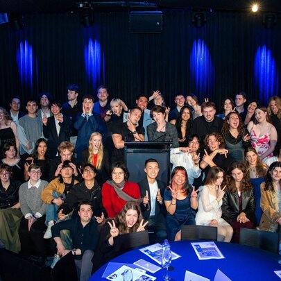 A large group of attendees gathering on stage at the Australia Youth Film Festival ceremony.