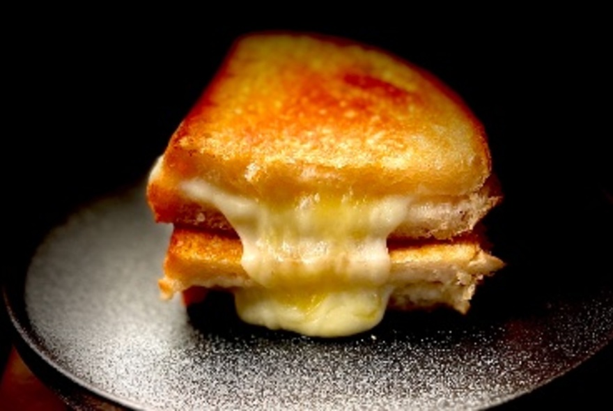 A very cheesy toasted sandwich cut in half on a plate.