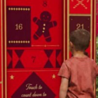 A life-sized interactive digital advent calendar with a child standing in front of it.