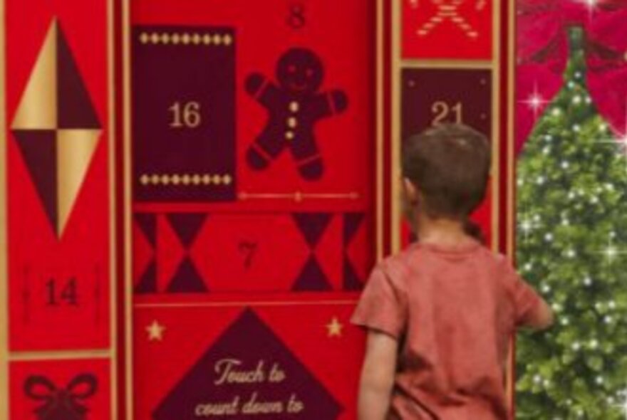 A life-sized interactive digital advent calendar with a child standing in front of it.