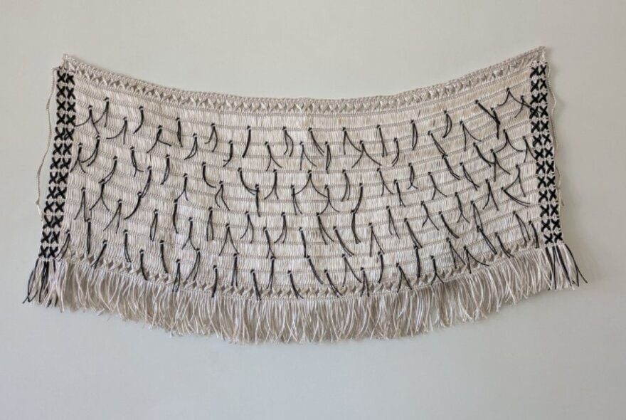 A traditional Māori cloak hanging on a wall. 