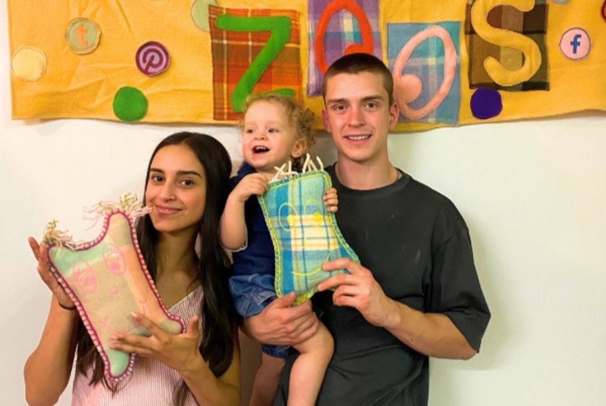 Family holding child and wool toy.