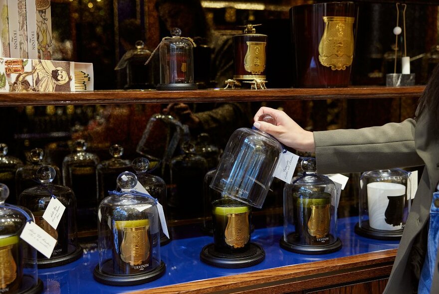 A woman lifting a cloche off a candle in a store.