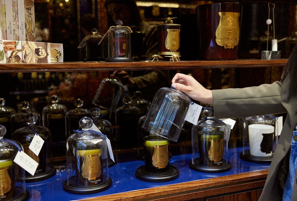 A woman lifting a cloche off a candle in a store.